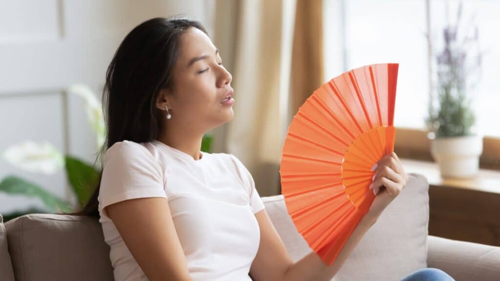 woman using fan to stay cool
