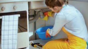 homeowner dealing with a leaky pipe under a sink